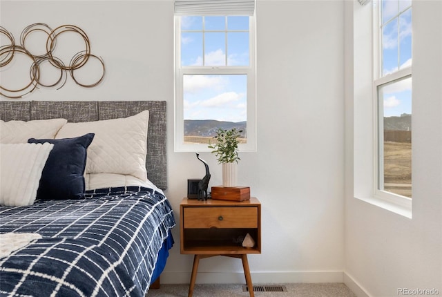 carpeted bedroom featuring baseboards, multiple windows, and visible vents