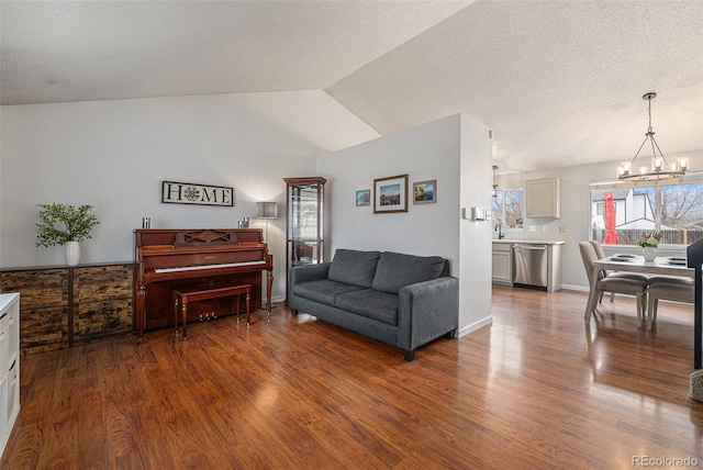 living area with vaulted ceiling, a textured ceiling, an inviting chandelier, and wood finished floors