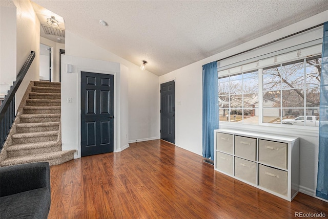 foyer entrance featuring stairs, lofted ceiling, a textured ceiling, and wood finished floors