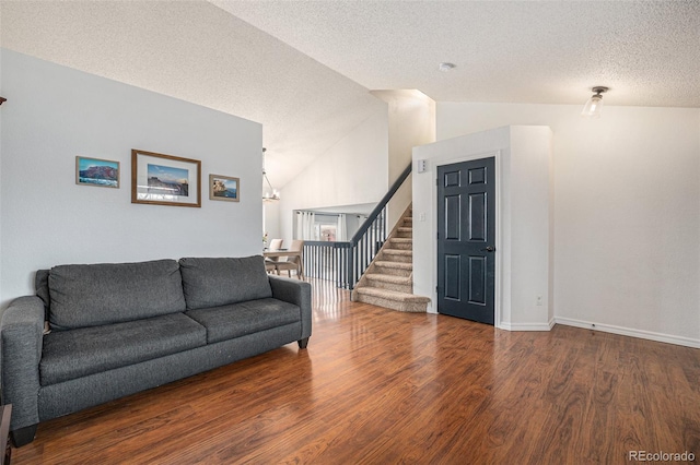 living area with baseboards, lofted ceiling, wood finished floors, stairs, and a textured ceiling