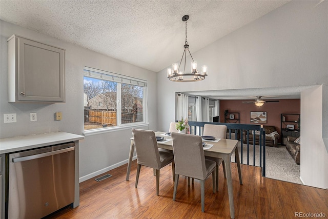 dining area with baseboards, visible vents, lofted ceiling, wood finished floors, and a textured ceiling