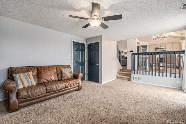 living area featuring a textured ceiling, ceiling fan with notable chandelier, baseboards, stairway, and carpet