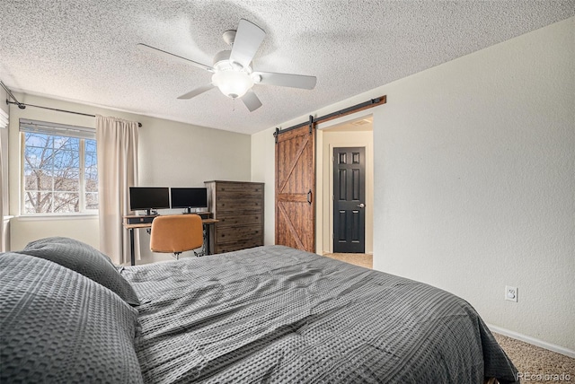 bedroom featuring a barn door, a ceiling fan, a textured wall, a textured ceiling, and carpet floors