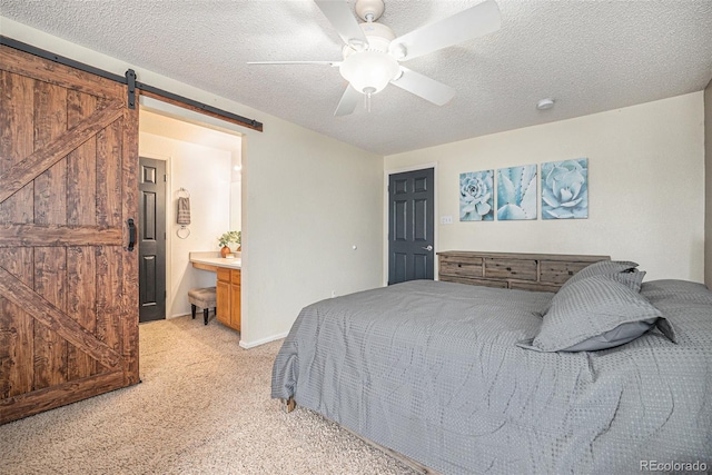 bedroom featuring a barn door, ceiling fan, a textured ceiling, and light colored carpet