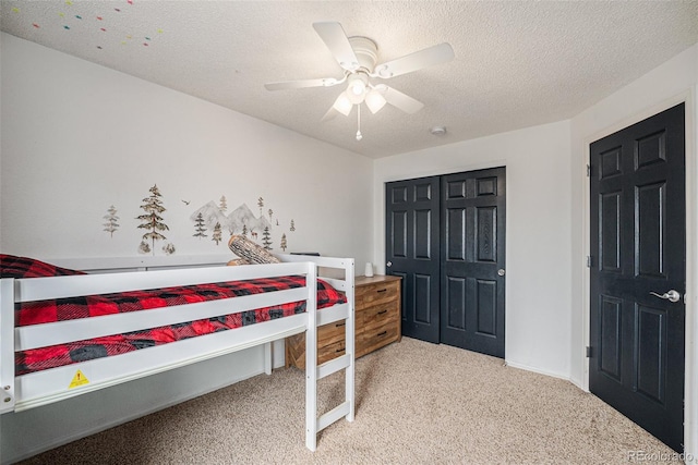 bedroom featuring a textured ceiling, carpet floors, a closet, and a ceiling fan