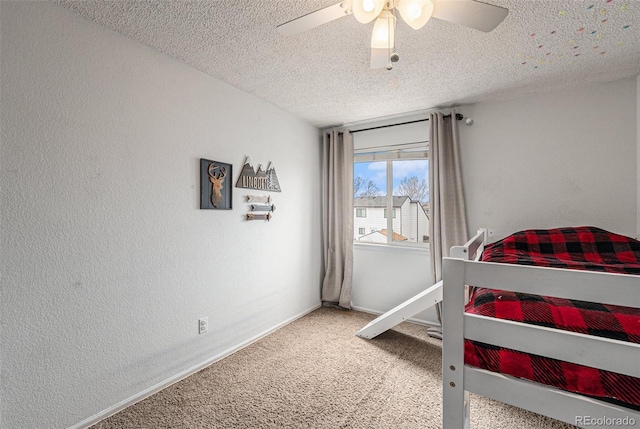 carpeted bedroom with a textured ceiling, a textured wall, a ceiling fan, and baseboards