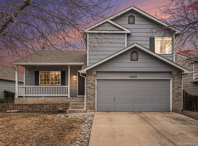 split level home featuring covered porch, brick siding, driveway, and an attached garage