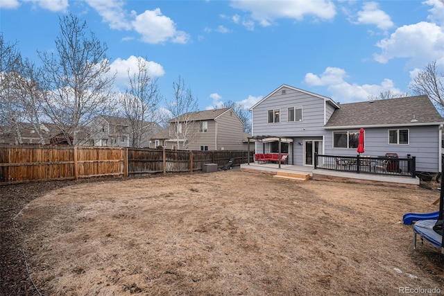 rear view of house with a fenced backyard, a deck, and roof with shingles