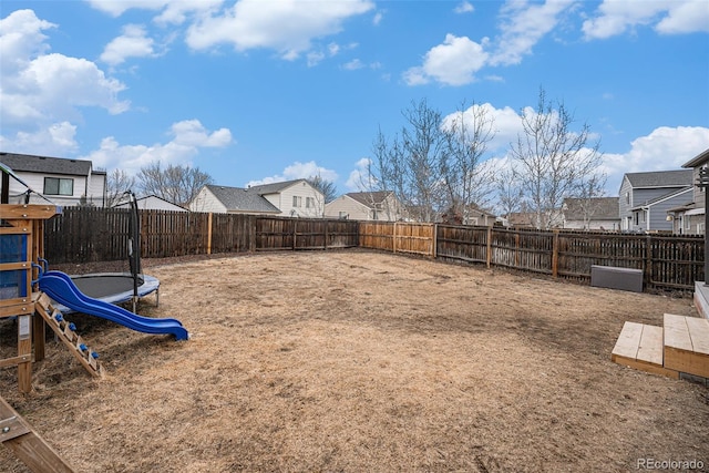 view of yard with a trampoline, a fenced backyard, and a residential view