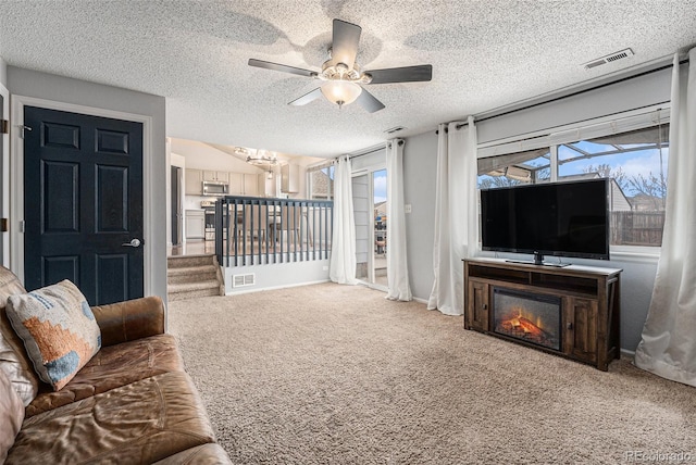 living room featuring carpet, visible vents, a textured ceiling, and baseboards