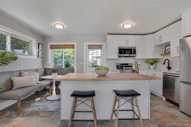 9400 Ridge Rd, Arvada, CO 80002 - kitchen featuring appliances with stainless steel finishes, wooden counters, stone tile flooring, and a breakfast bar area