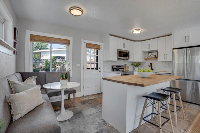 9400 Ridge Rd, Arvada, CO 80002 - kitchen with appliances with stainless steel finishes, wooden counters, healthy amount of natural light, and a kitchen bar