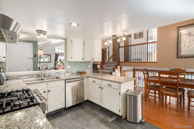 7582 Jared Way, Littleton, CO 80125 - kitchen with dishwasher, wall chimney exhaust hood, a peninsula, white cabinets, and gas range