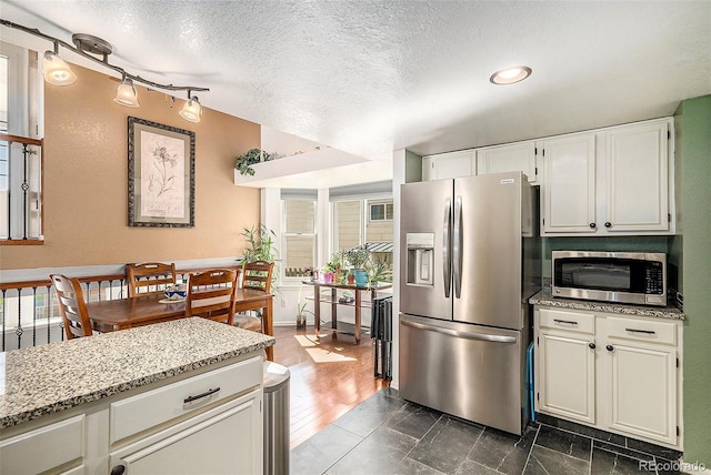 7582 Jared Way, Littleton, CO 80125 - kitchen featuring appliances with stainless steel finishes, track lighting, a textured ceiling, light stone countertops, and white cabinets