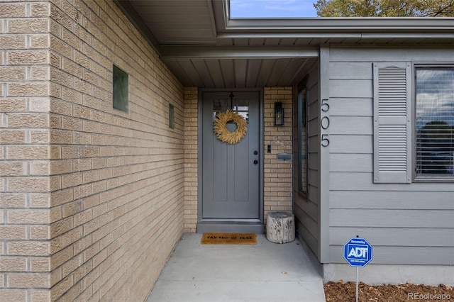 view of exterior entry featuring brick siding