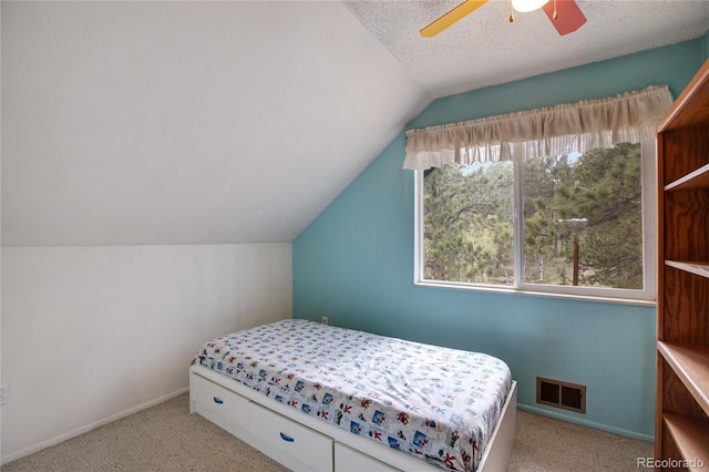 carpeted bedroom with ceiling fan, a textured ceiling, and vaulted ceiling