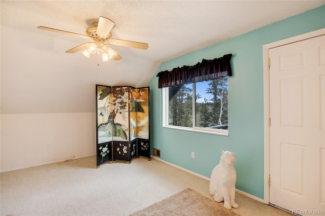 interior space with a textured ceiling, ceiling fan, carpet floors, and vaulted ceiling