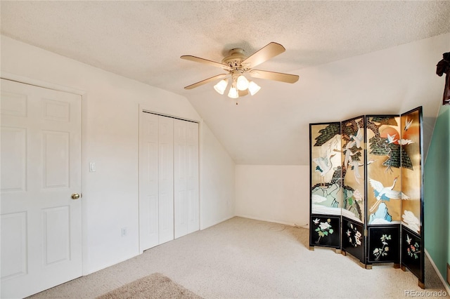 additional living space with a textured ceiling, ceiling fan, carpet, and vaulted ceiling