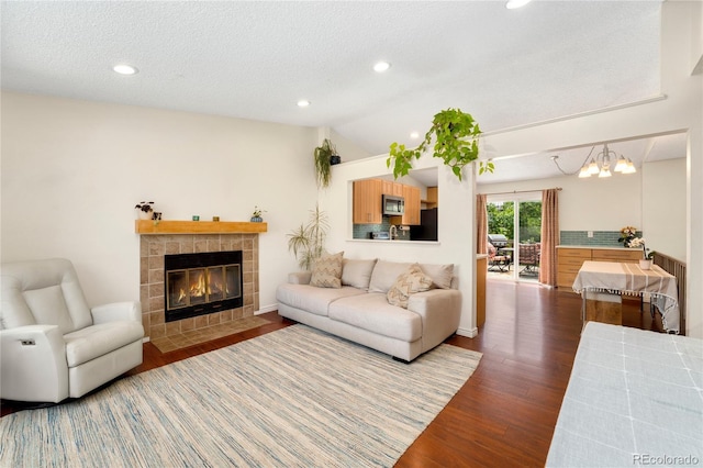 9376 W Wagon Trail Cir, Littleton, CO 80123 - living room with dark wood-type flooring, a tiled fireplace, lofted ceiling, recessed lighting, and a textured ceiling