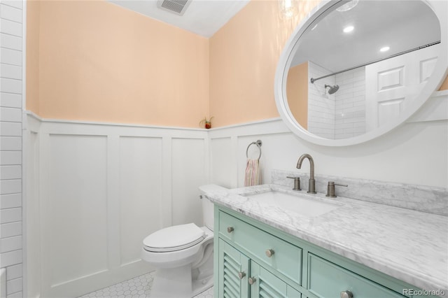 9376 W Wagon Trail Cir, Littleton, CO 80123 - bathroom featuring toilet, vanity, a wainscoted wall, tile patterned floors, and a decorative wall