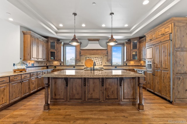 kitchen with light stone counters, a tray ceiling, and paneled built in fridge