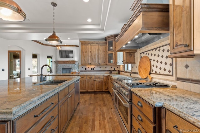 kitchen featuring stainless steel appliances, light stone countertops, sink, and custom range hood