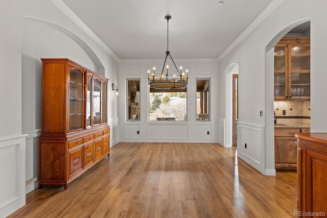 unfurnished dining area with crown molding, a chandelier, and light hardwood / wood-style floors