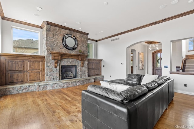 living room with ornamental molding, plenty of natural light, a fireplace, and light hardwood / wood-style floors