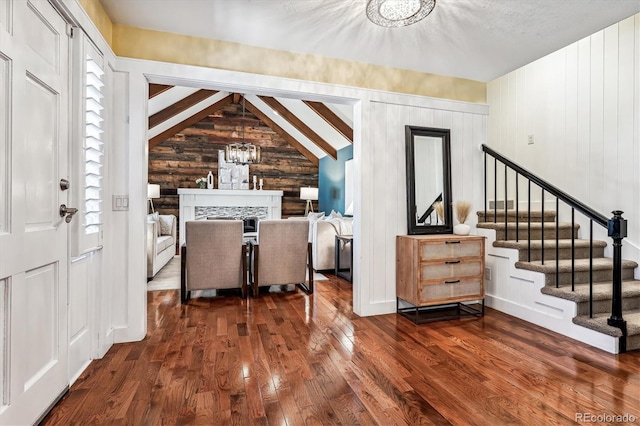 foyer featuring a chandelier, vaulted ceiling with beams, dark hardwood / wood-style floors, and wooden walls