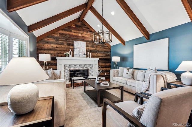 living room with beam ceiling, a stone fireplace, wood walls, and a notable chandelier