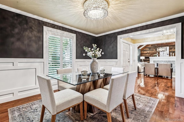 dining area featuring a notable chandelier, wood-type flooring, crown molding, and log walls