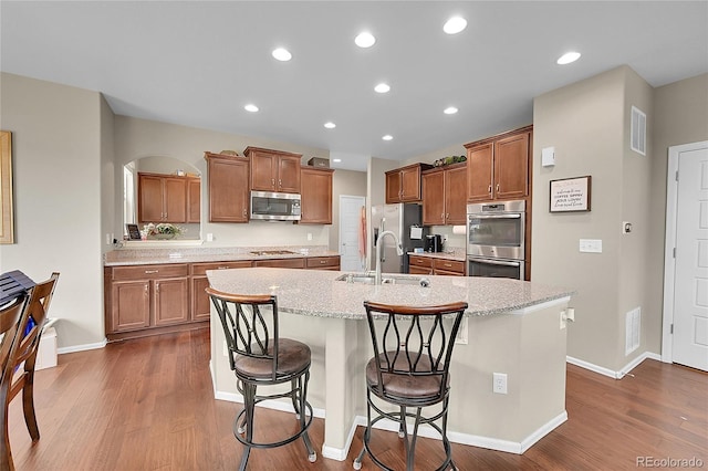 kitchen with a breakfast bar, sink, a center island with sink, and appliances with stainless steel finishes