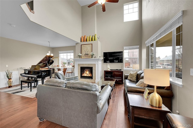 living room featuring hardwood / wood-style flooring, ceiling fan with notable chandelier, and a high ceiling