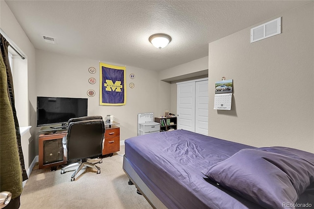 carpeted bedroom featuring a textured ceiling and a closet