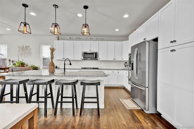 kitchen featuring white cabinetry, hanging light fixtures, a center island with sink, and appliances with stainless steel finishes