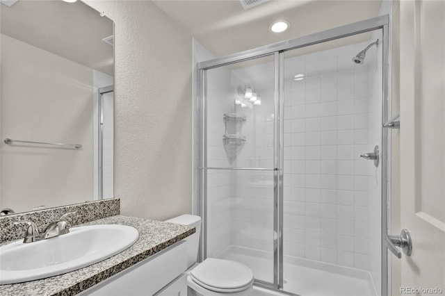 bathroom with vanity, a shower with shower door, and toilet