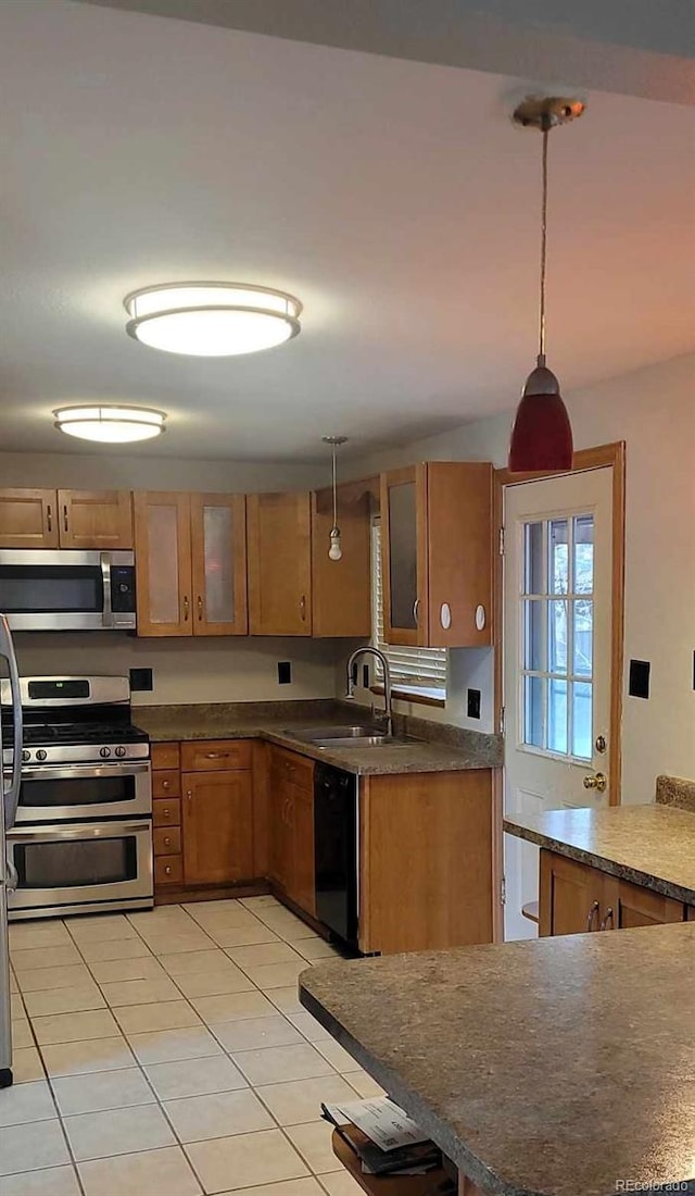 kitchen featuring sink, light tile patterned floors, appliances with stainless steel finishes, decorative light fixtures, and kitchen peninsula