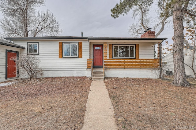 single story home featuring covered porch and a chimney