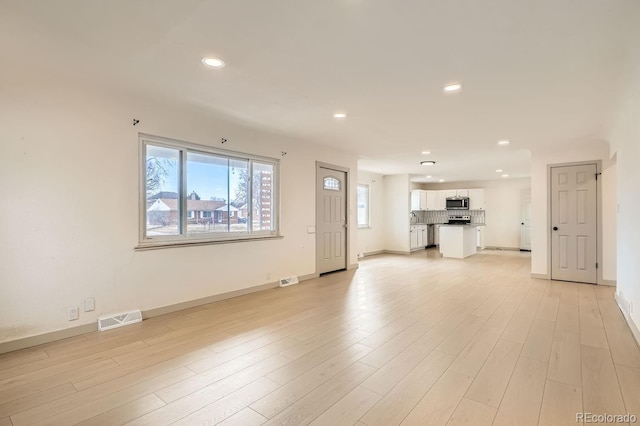 unfurnished living room featuring recessed lighting, baseboards, visible vents, and light wood finished floors