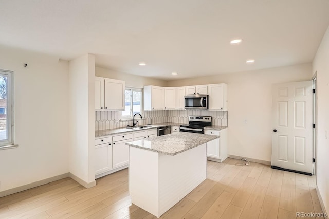 kitchen with stainless steel appliances, light wood finished floors, backsplash, and white cabinets