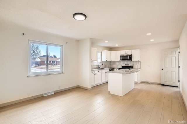 kitchen featuring tasteful backsplash, visible vents, stainless steel appliances, light wood-style floors, and white cabinetry