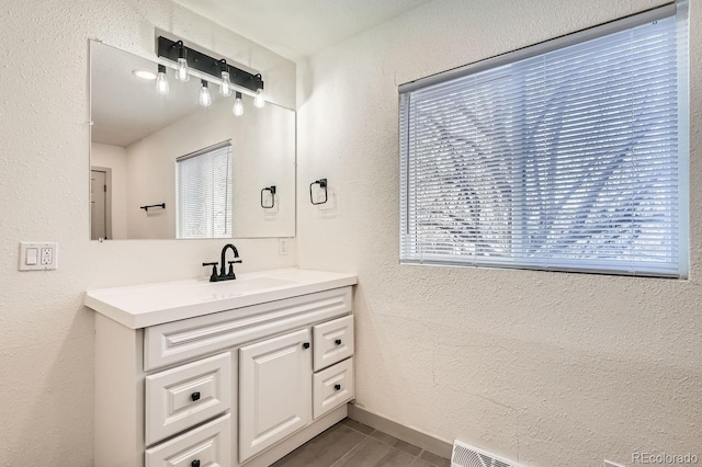 bathroom with vanity, baseboards, and a textured wall