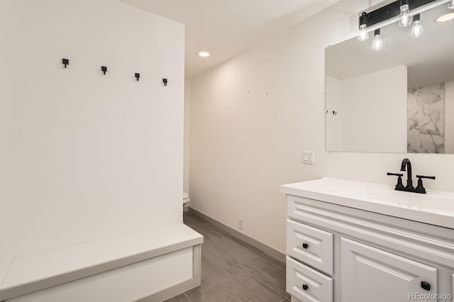 bathroom with recessed lighting, baseboards, vanity, and toilet