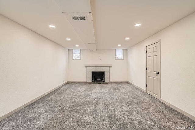 basement with carpet, visible vents, a fireplace, and baseboards