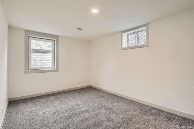 empty room with a wealth of natural light, carpet, visible vents, and baseboards