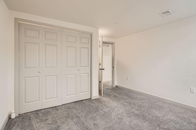 unfurnished bedroom with a closet, carpet flooring, visible vents, and baseboards