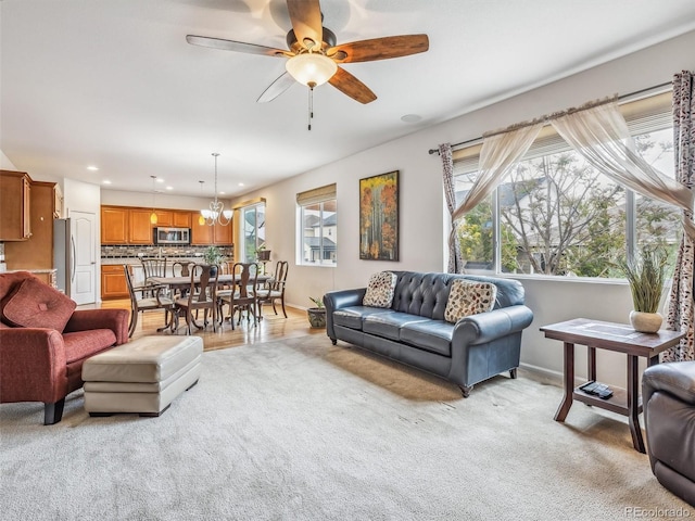 living area with ceiling fan with notable chandelier, baseboards, light colored carpet, and recessed lighting