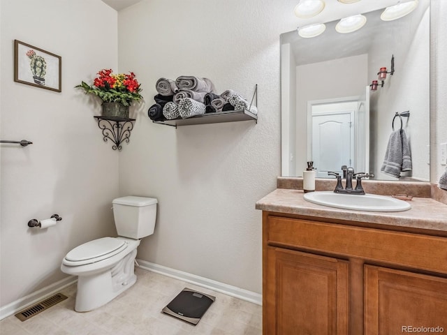 bathroom featuring toilet, vanity, visible vents, and baseboards