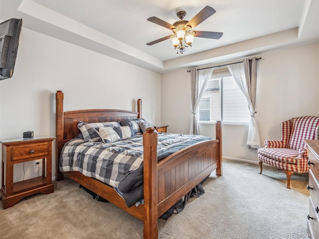 bedroom featuring a ceiling fan, a raised ceiling, light colored carpet, and baseboards