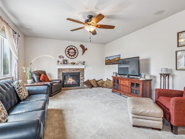 carpeted living area featuring ceiling fan and a fireplace